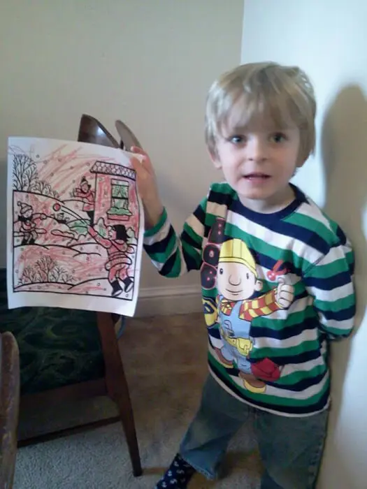 Young child showing a colorful holiday drawing for the Alexandria Children's Dentistry Holiday Art Raffle
