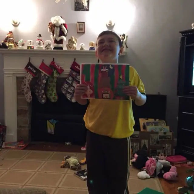 Child holding a handmade Christmas gift artwork for the Alexandria Children's Dentistry Holiday Art Raffle