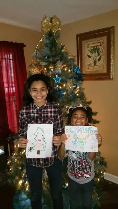 Two children displaying Christmas drawings for the Alexandria Children's Dentistry Holiday Art Raffle
