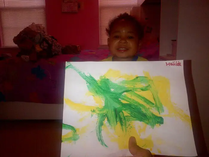 Child displaying a bright holiday painting for the Alexandria Children's Dentistry Holiday Art Raffle