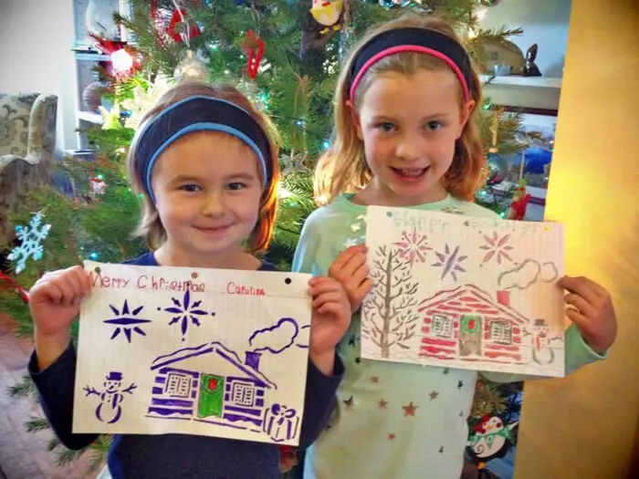 Two children holding colorful Christmas drawings for the Alexandria Children's Dentistry Holiday Art Raffle
