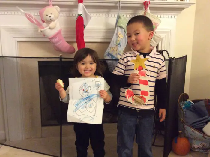 Two children proudly displaying holiday artwork for the Alexandria Children's Dentistry Holiday Art Raffle
