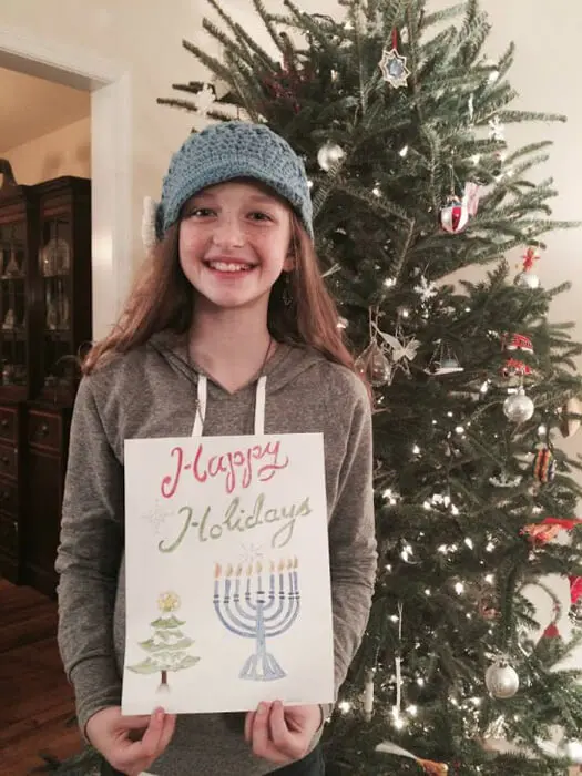 Child displaying a Hanukkah holiday drawing for the Alexandria Children's Dentistry Holiday Art Raffle