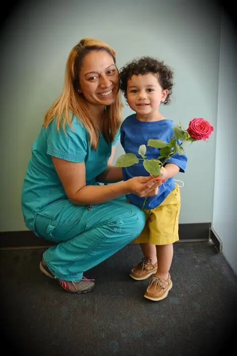 Alexandria Children's Dentistry team member giving a child a Mother's Day rose