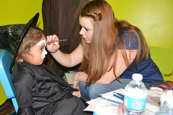 Alexandria Children's Dentistry team member painting a child's face at the Pooch Plunge