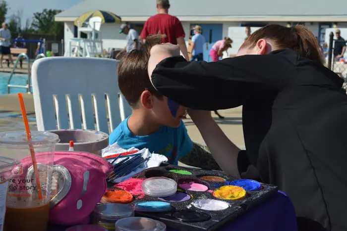 Child participating in a face painting activity at the Alexandria Children's Dentistry event