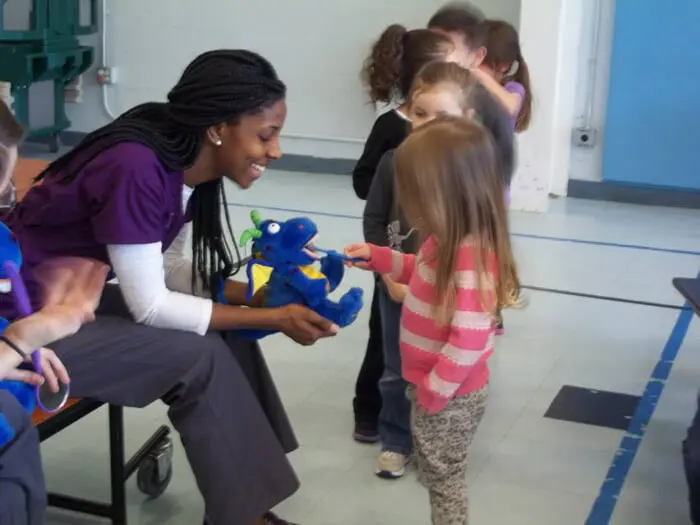 Alexandria Children's Dentistry educator engaging a student in a hands-on oral health lesson