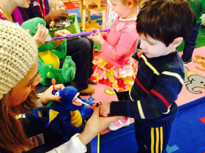 Child interacting with Alexandria Children's Dentistry mascot during a school dental education program